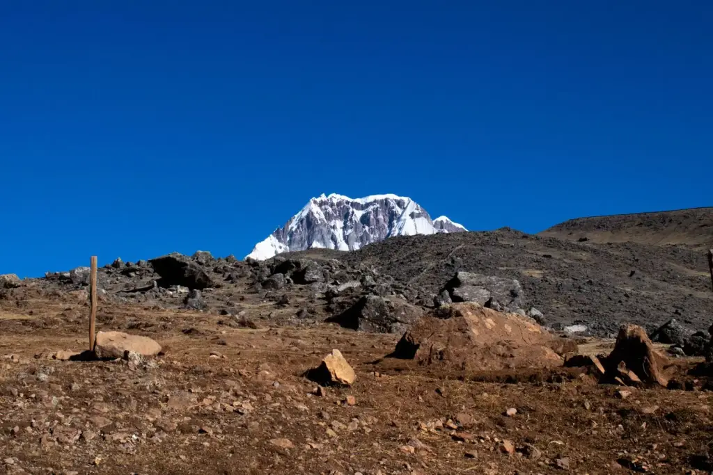 The snow-covered summit of Ausangate rising above rocky high-altitude grassland