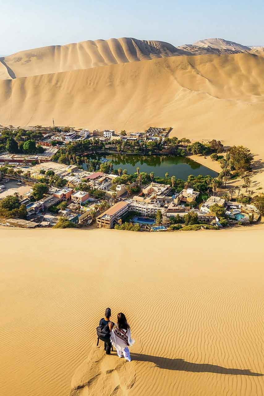 The Huacachina oasis and lagoon surrounded by tall sand dunes near Ica