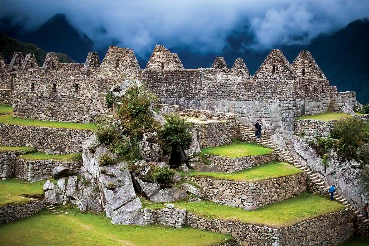 Gabled stone houses and terraces at Machu Picchu under low clouds