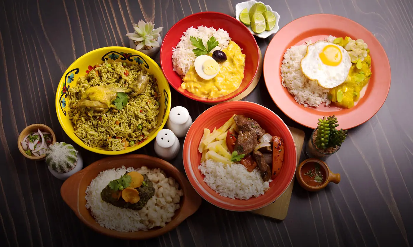 Classic Peruvian dishes on a table, including lomo saltado, ají de gallina and arroz con pollo