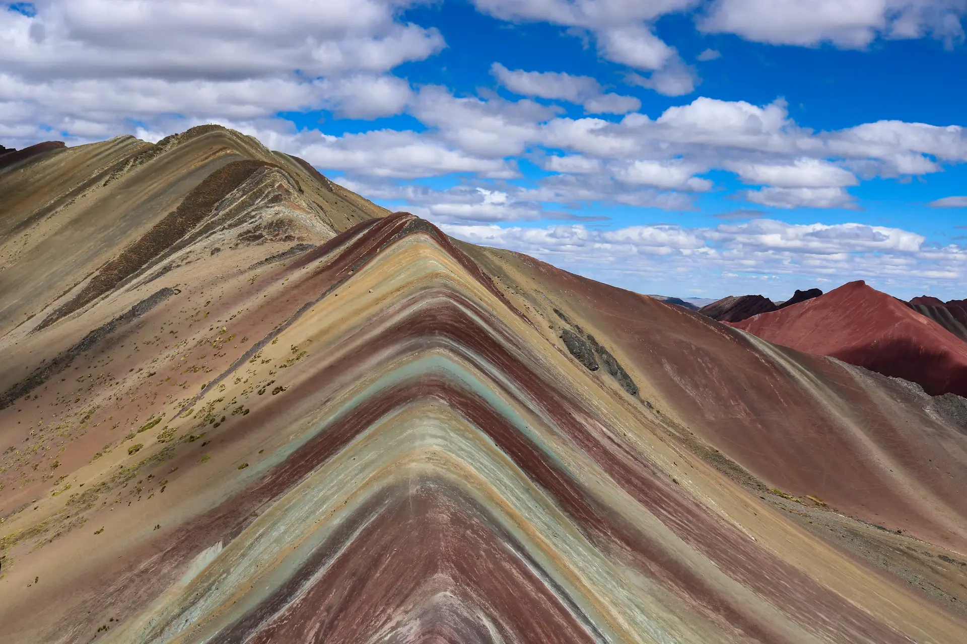 Striped mineral slopes of Vinicunca, the Rainbow Mountain, under a blue sky